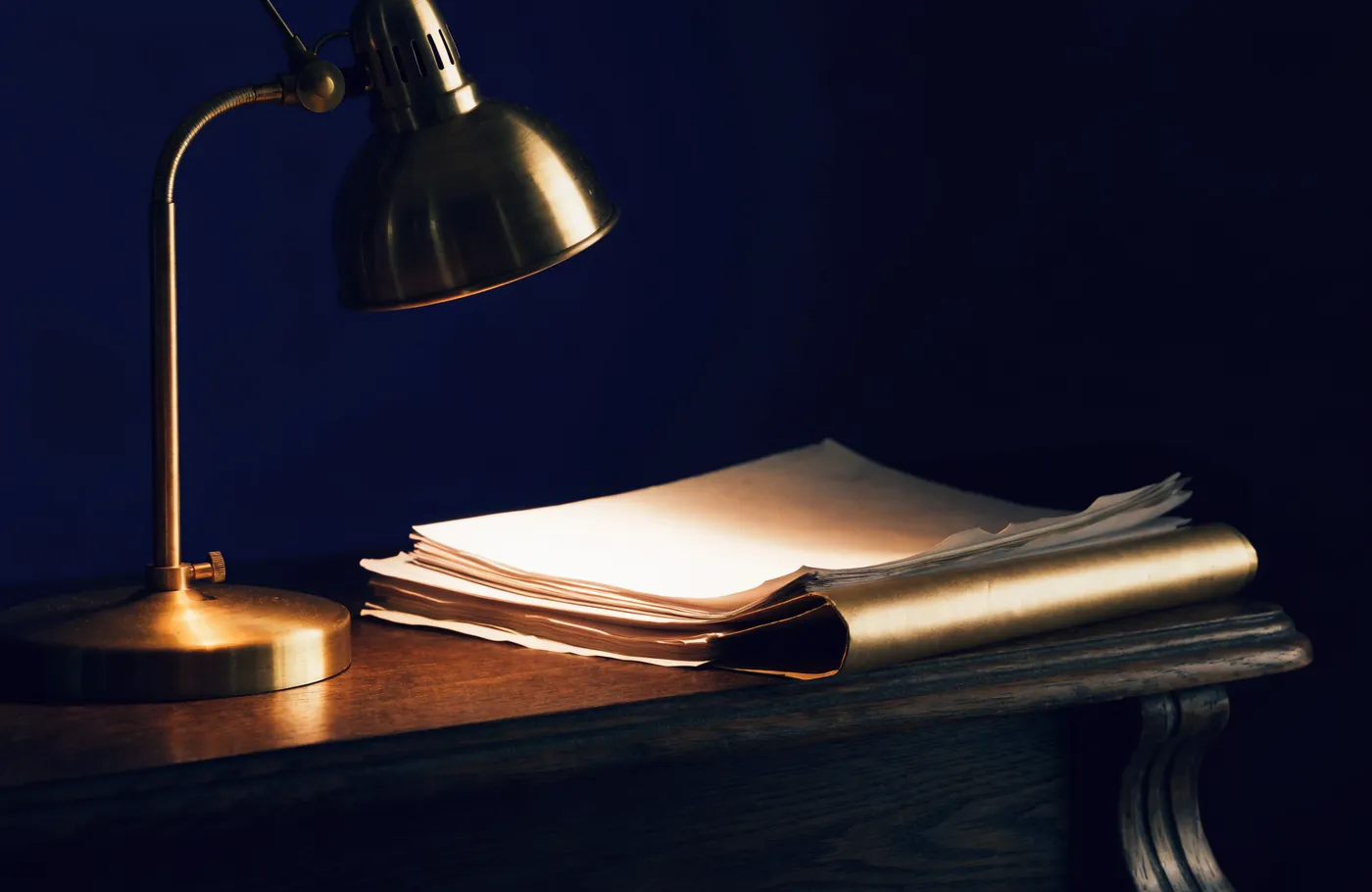 Loose papers gathered into a single folder under a desk lamp