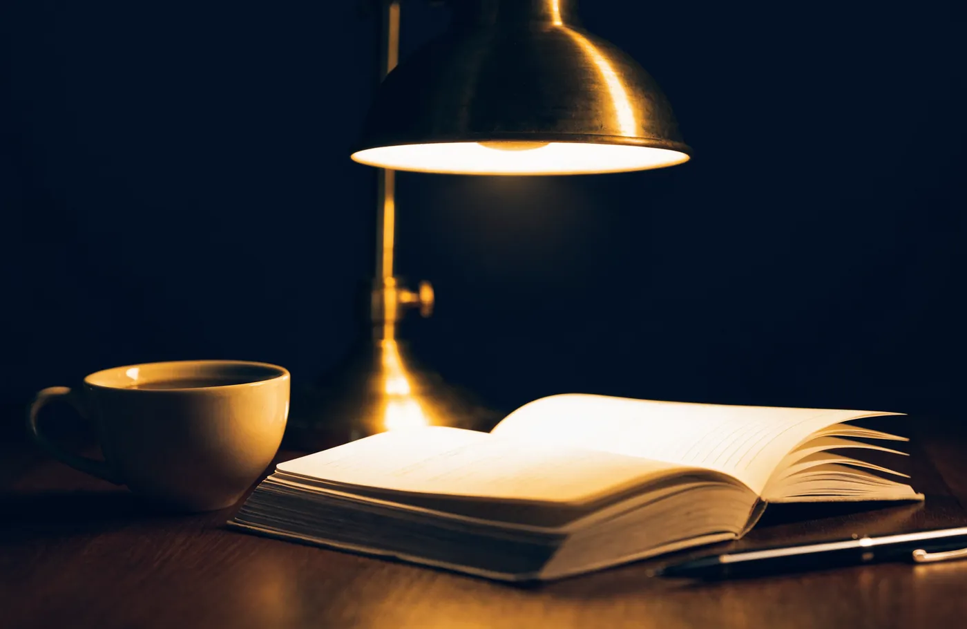 Un carnet de budget et une tasse de cafe sous une lampe