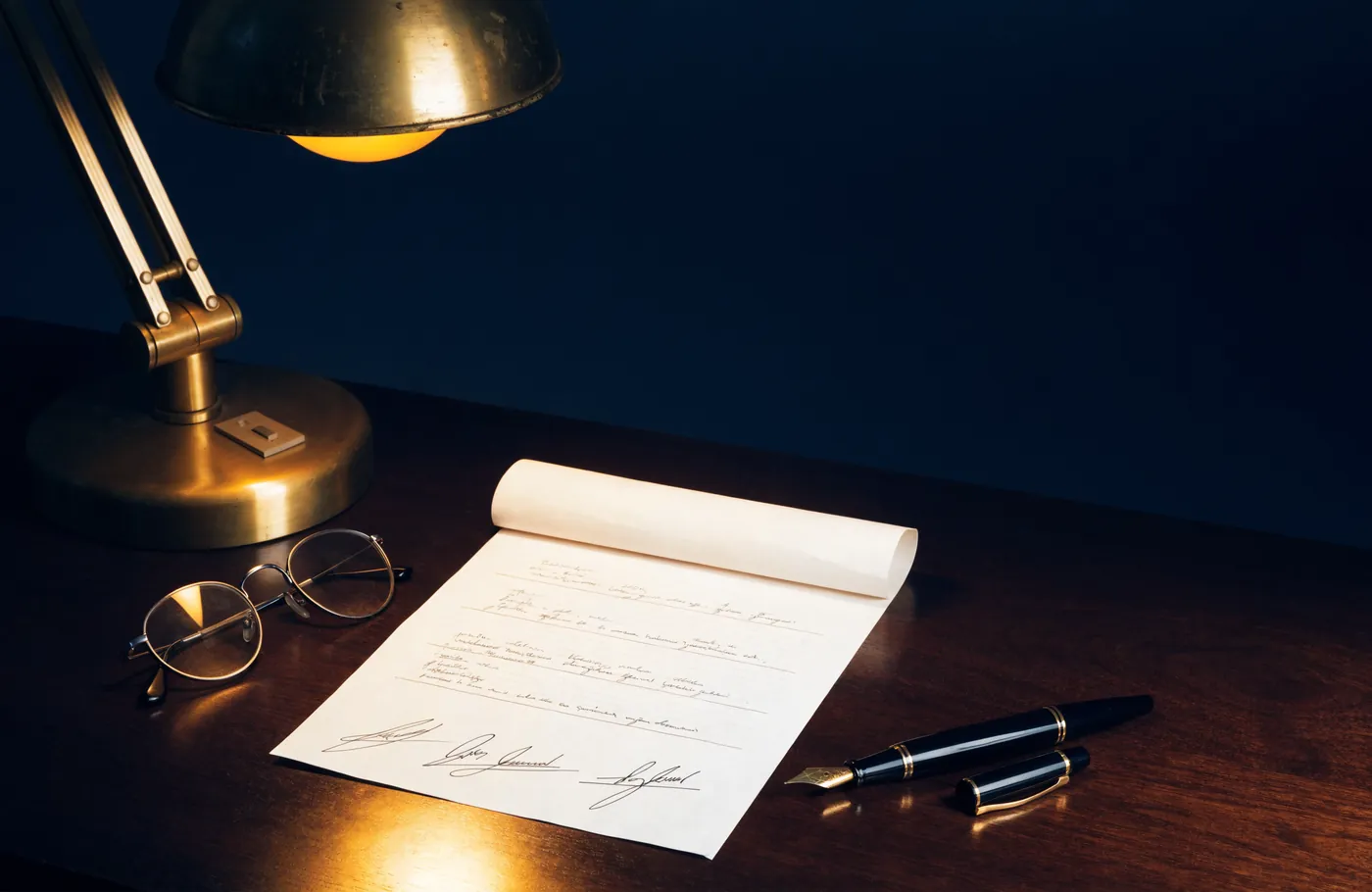 Un contrat signe et un stylo plume sous une lampe de bureau